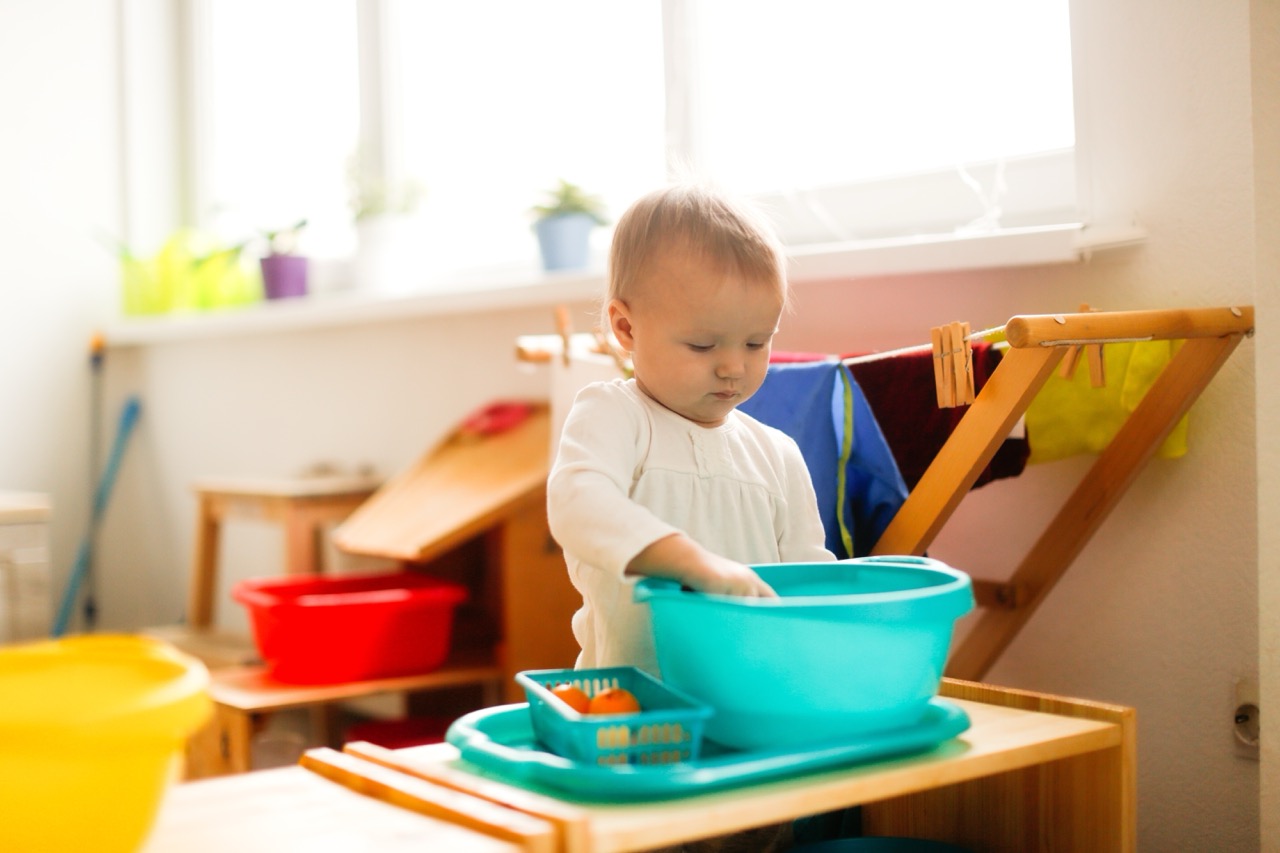 Toddler child playing with water in a basin